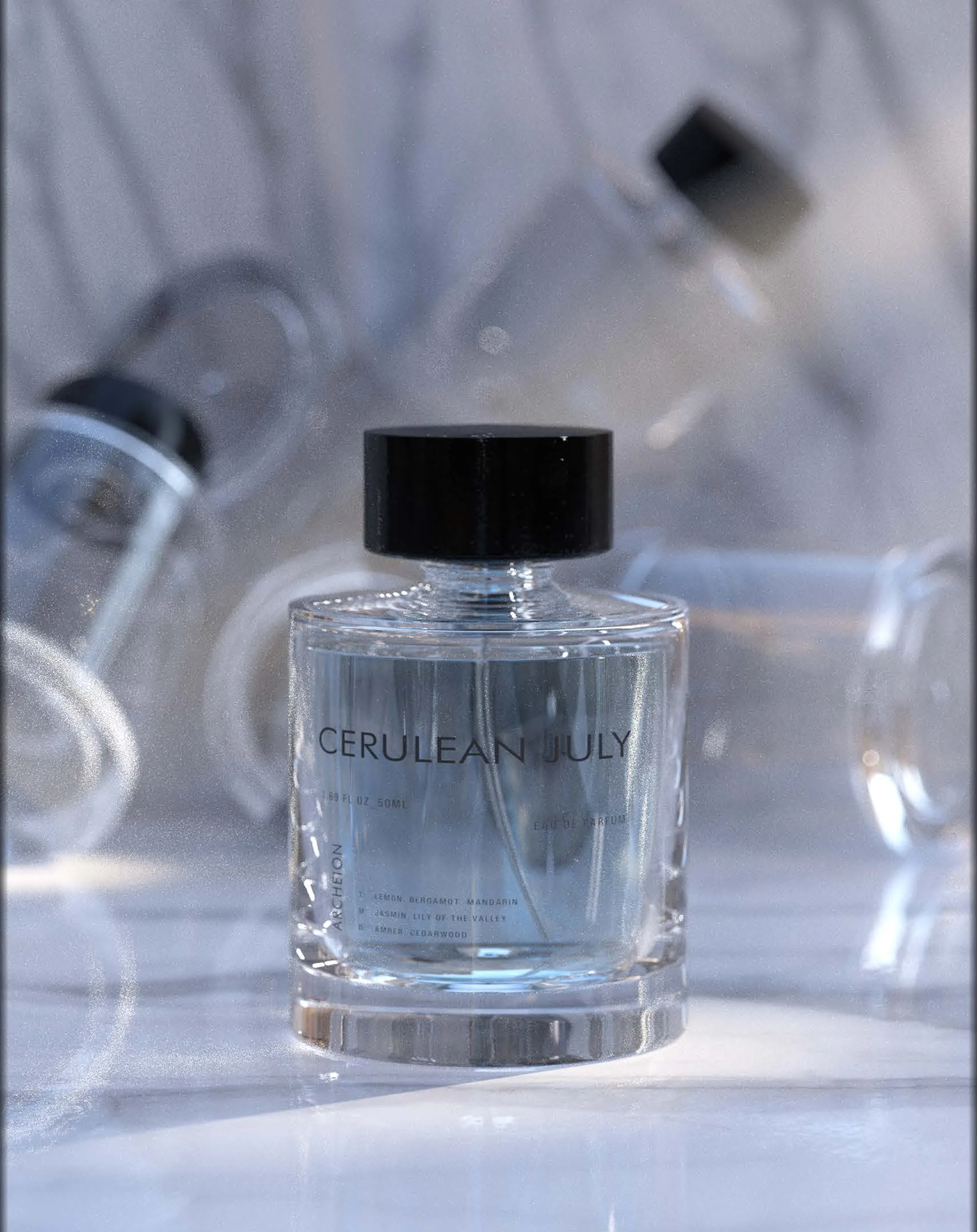 Cerulean July: the bottle on marble with glass bottles blurred behind