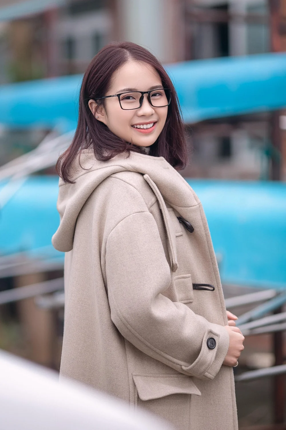 Portrait used for our persona, Jihyun Lee: a smiling young woman in glasses and a beige duffle coat