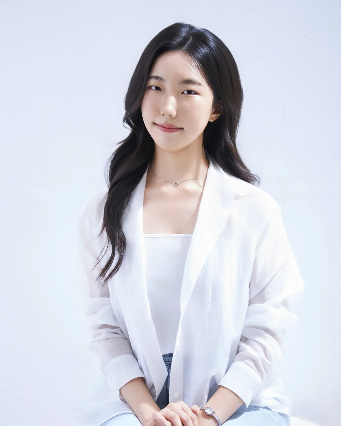 Jiyeong Yun, seated, in a white shirt and light jeans against a pale wall